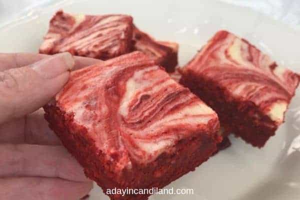 Red Velvet Cheesecake Brownies and hand holding one brownie