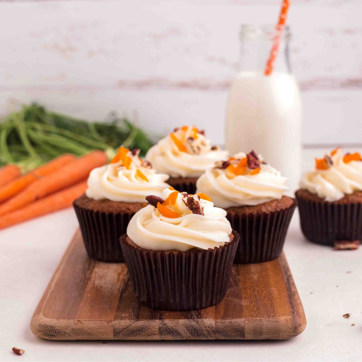 5 Moist Carrot Cake Cupcakes on wood stand with Glass of Milk.