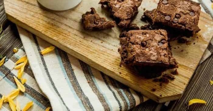 Fudgy chocolate chip brownies on a wooden board with a striped towel.