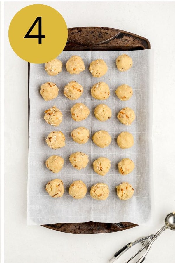 Dough balls rolled around Rolos, lined up on a parchment lined tray.