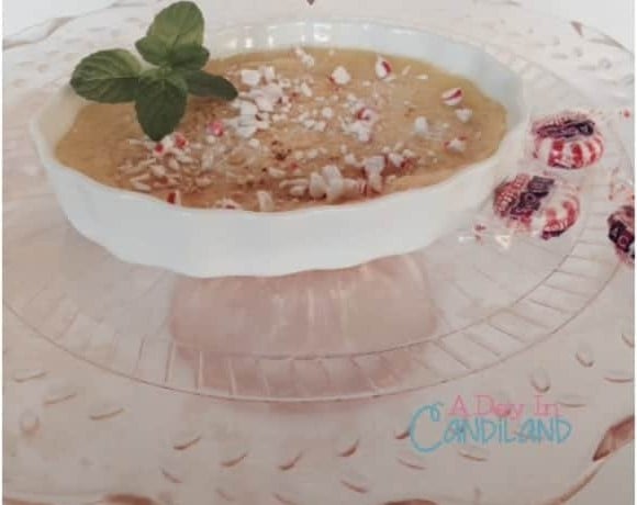 White chocolate peppermint creme brulee with crushed peppermint and fresh mint on a pink glass cake stand.