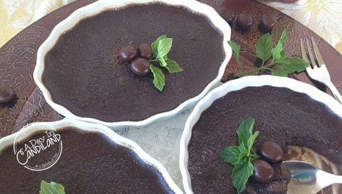 Three mocha espresso creme brulees topped with espresso beans and mint on a bronze charger.