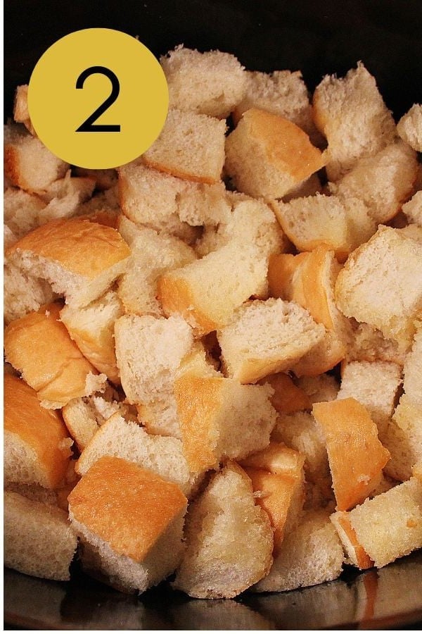 Bread cubes toasting in melted butter in the preheated crockpot.