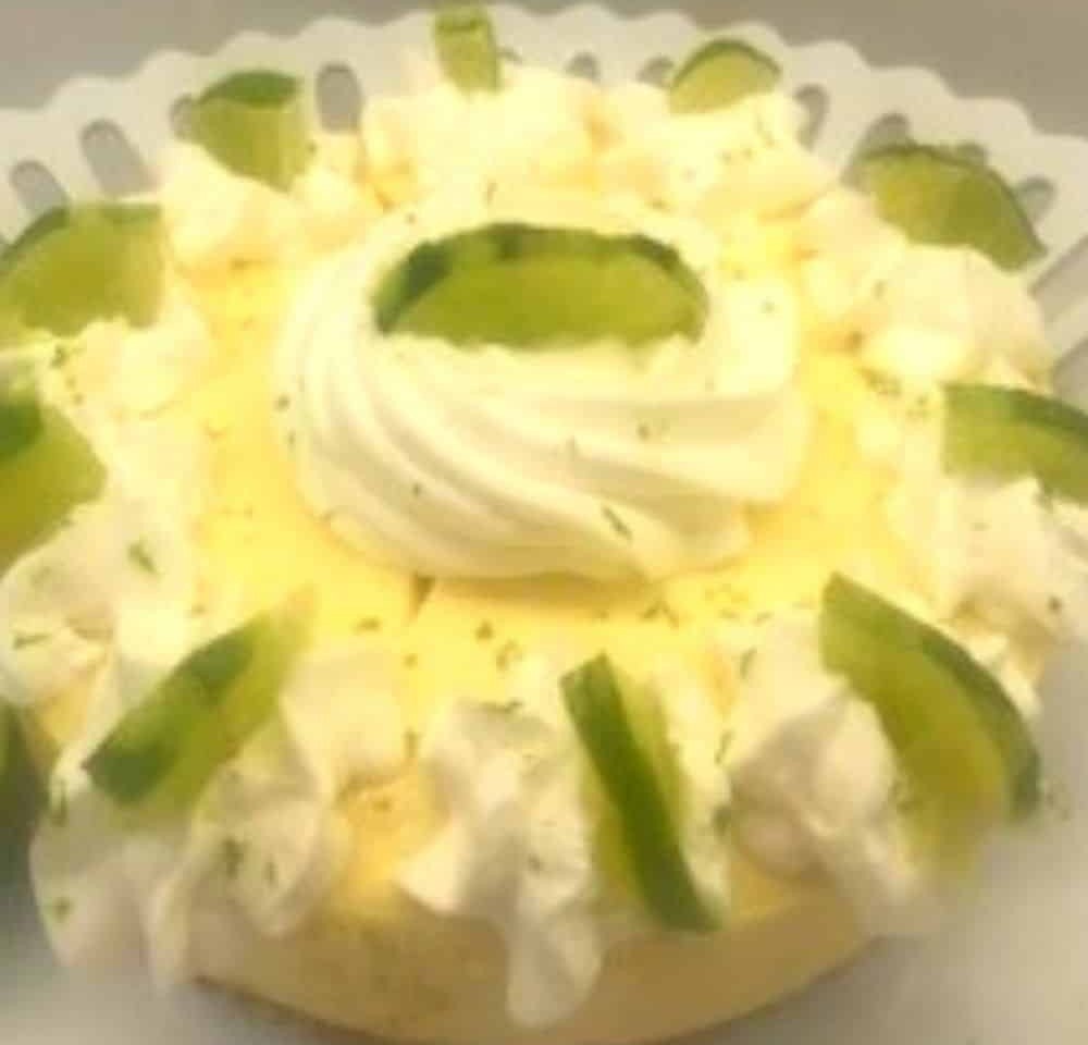 A whole Instant Pot key lime cheesecake topped with piped whipped cream, lime zest and lime slices.