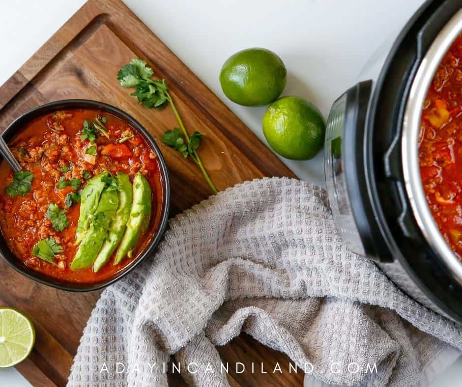 Bowl of Chili and white kitchen towel on butcher board. 