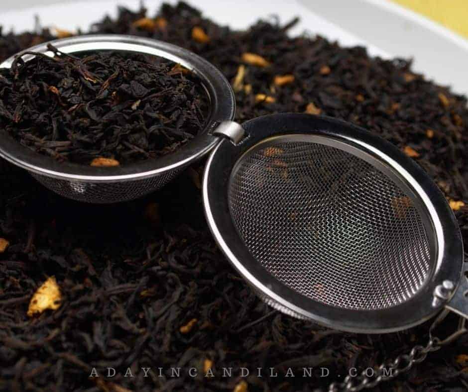 A bowl of loose leaf tea with a tea strainer inside of the bowl. 