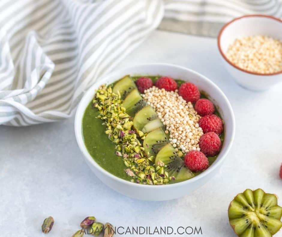 Green Smoothie bowl on table with napkin and a few ingredients 