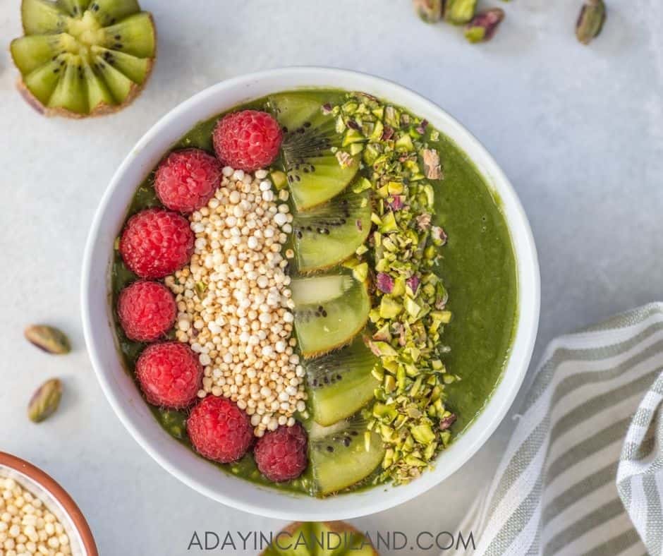 Green Smoothie Bowl with a striped napkin, and kiwi on the table. 