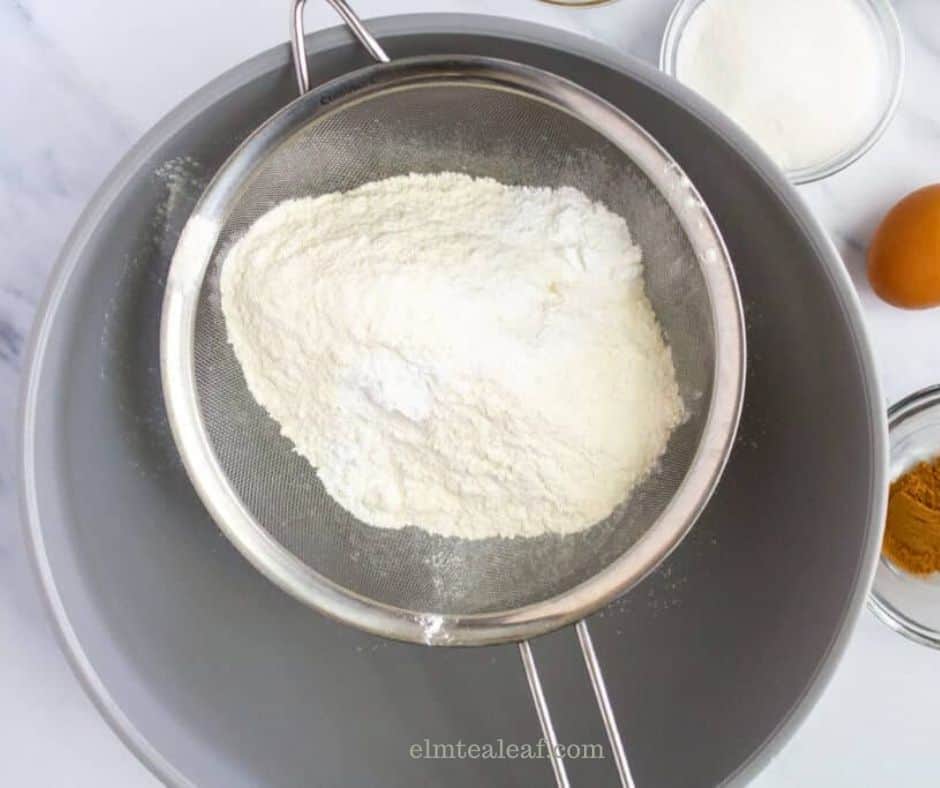 Flour, salt, sugar, baking powder and cinnamon sifted into a gray mixing bowl.