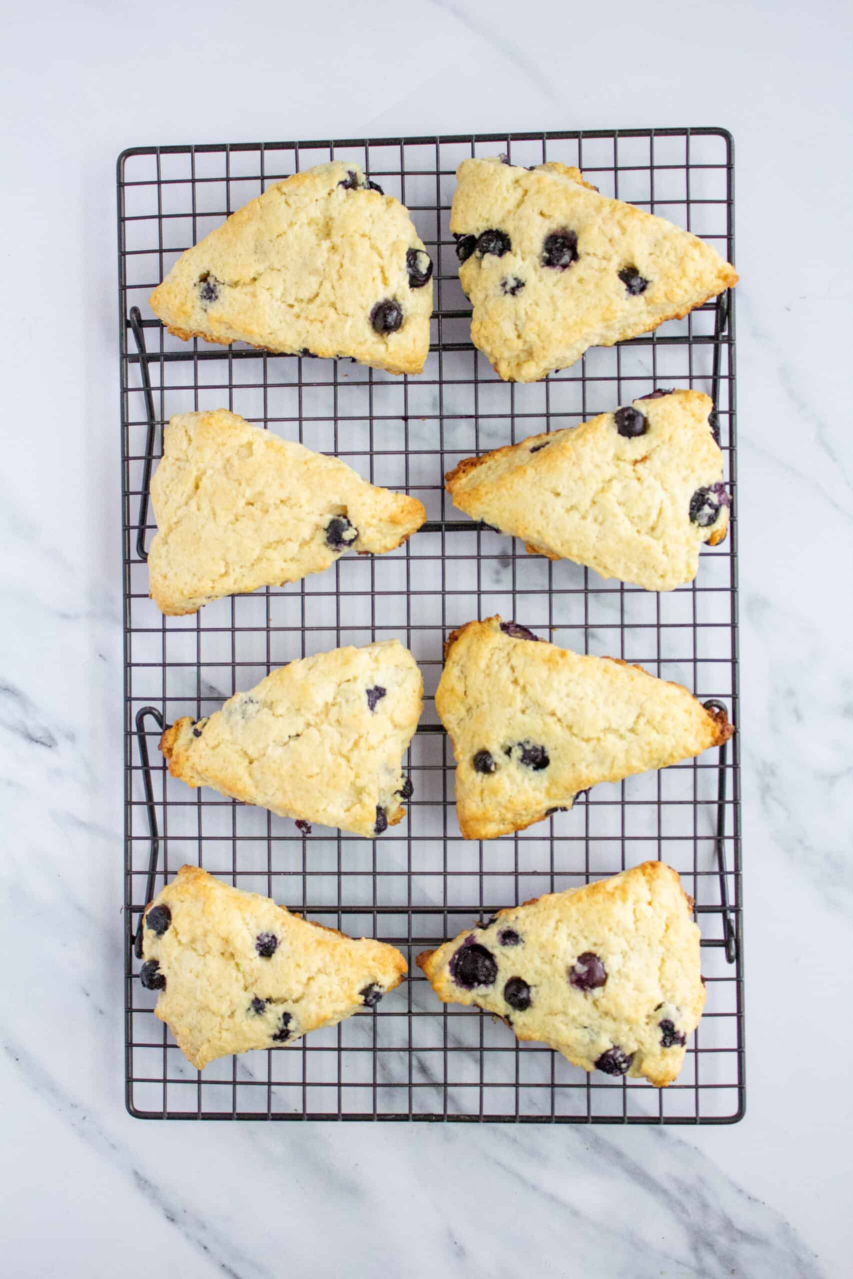 Golden baked blueberry scones cooling on a wire rack.