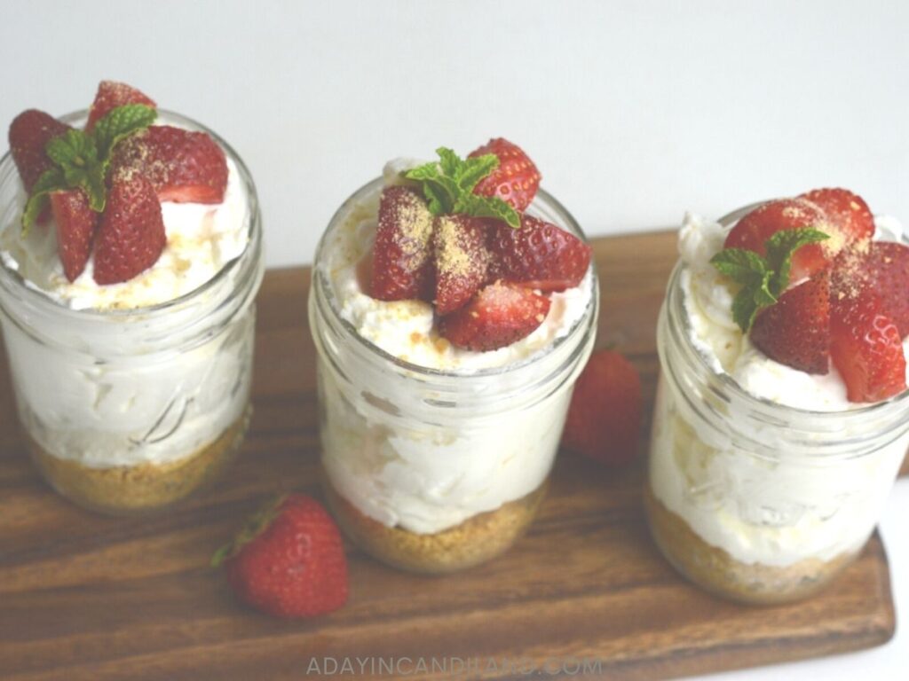 3 Jars of Strawberry Cheesecake on a wooden board. 
