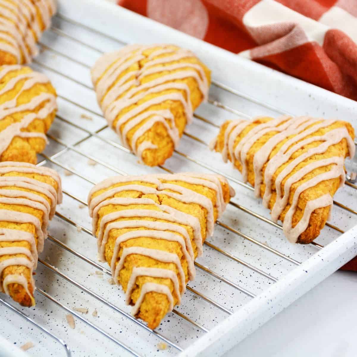 pumpkin scones sitting on a baking sheet drizzled with icing 