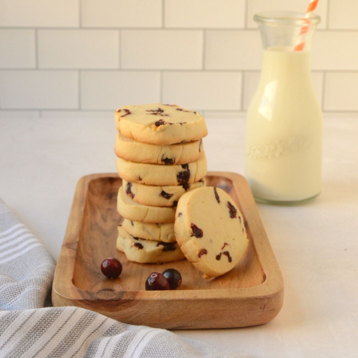 Stack of Cranberry Orange Shortbread Cookies with glass of milk.