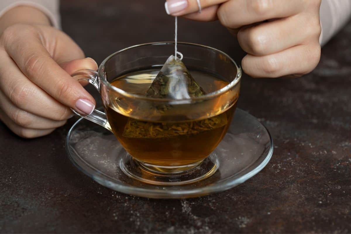 A Woman dipping a teabag into a cup of tea. 
