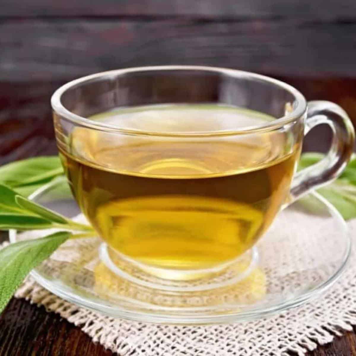 Clear cup of green tea on a white placemat. 