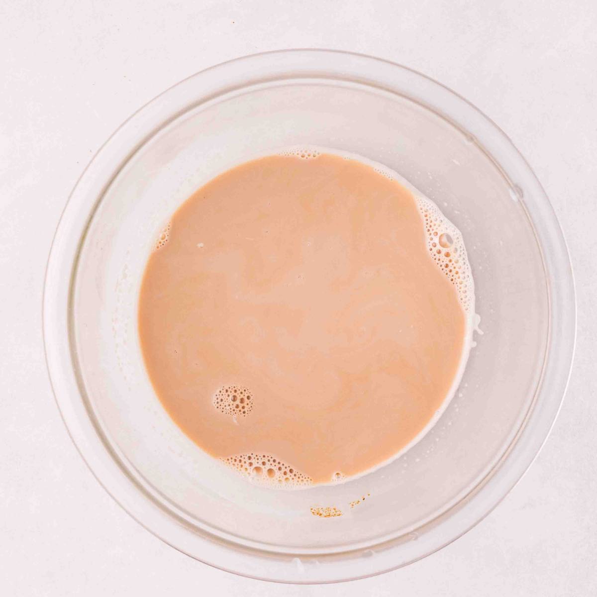 Espresso and warm milk stirred together in a bowl.