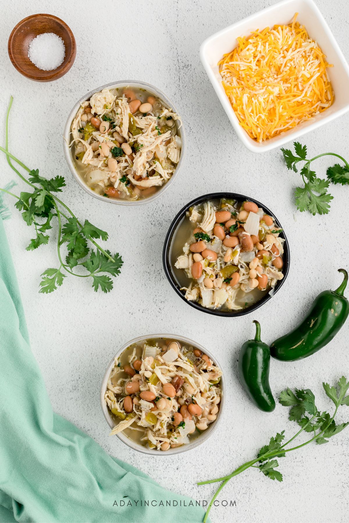 3 Bowls of White Chili with bowl of shredded cheese. 