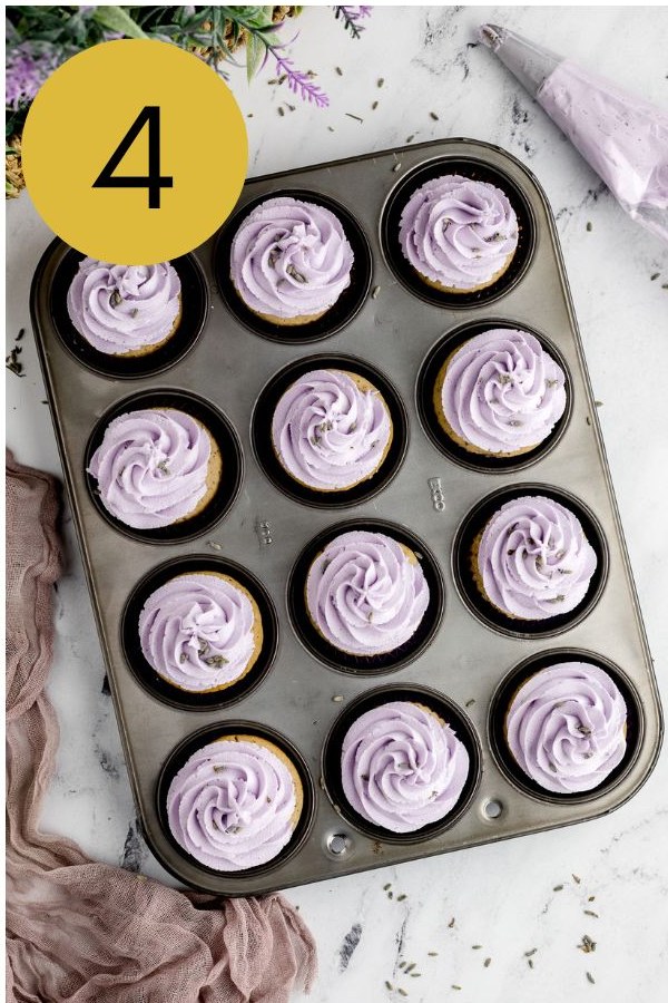 A pan of baked Earl Grey cupcakes piped with swirls of lavender buttercream.