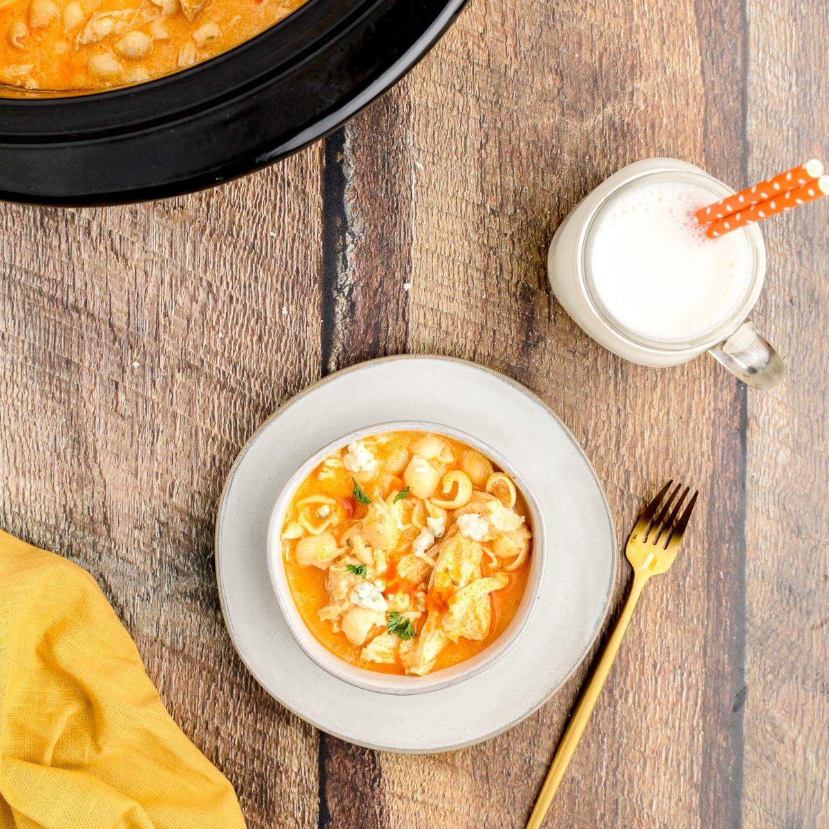 Buffalo Mac and Cheese in a bowl on a table with a glass of milk. 