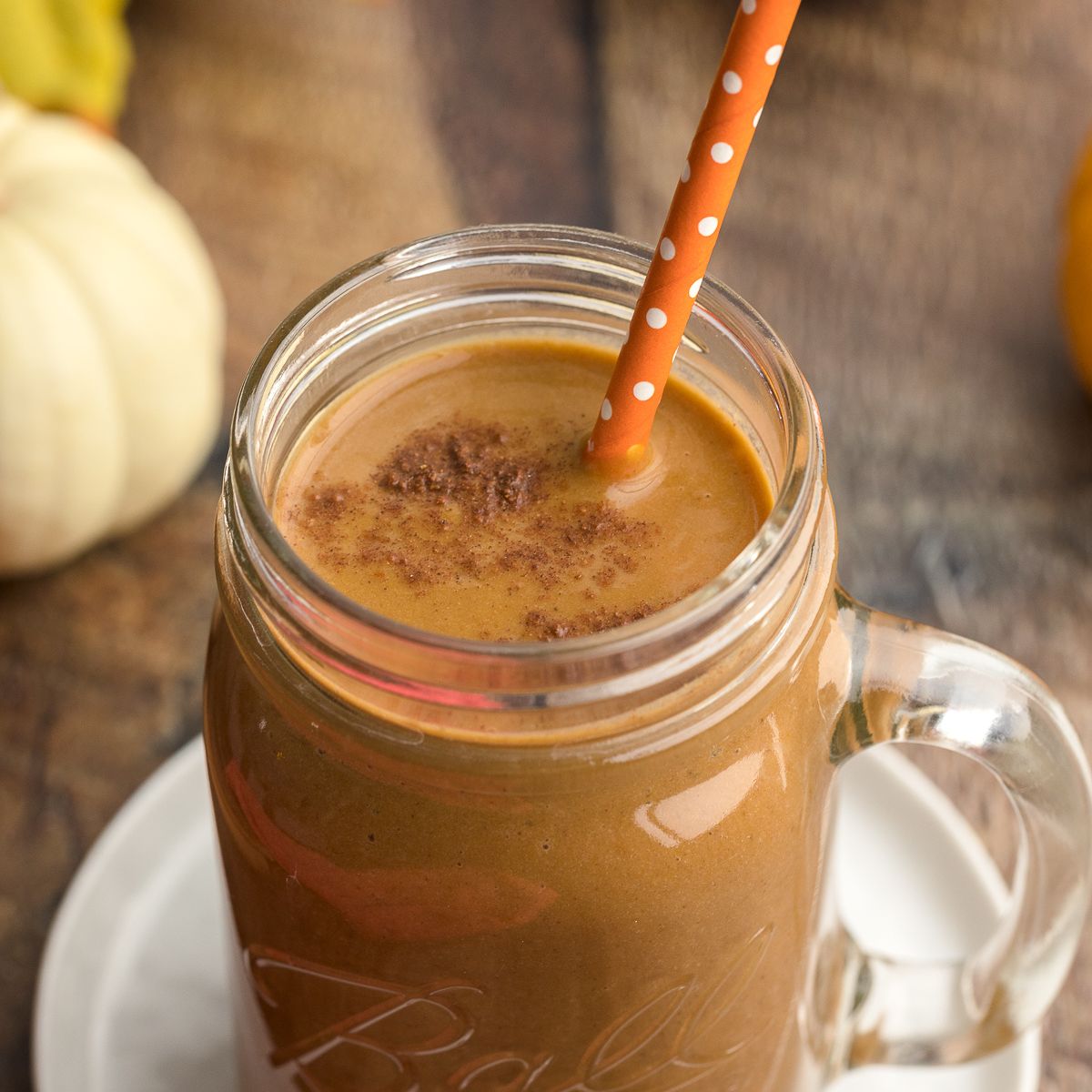 Pumpkin Protein Shake with an orange straw in a glass.