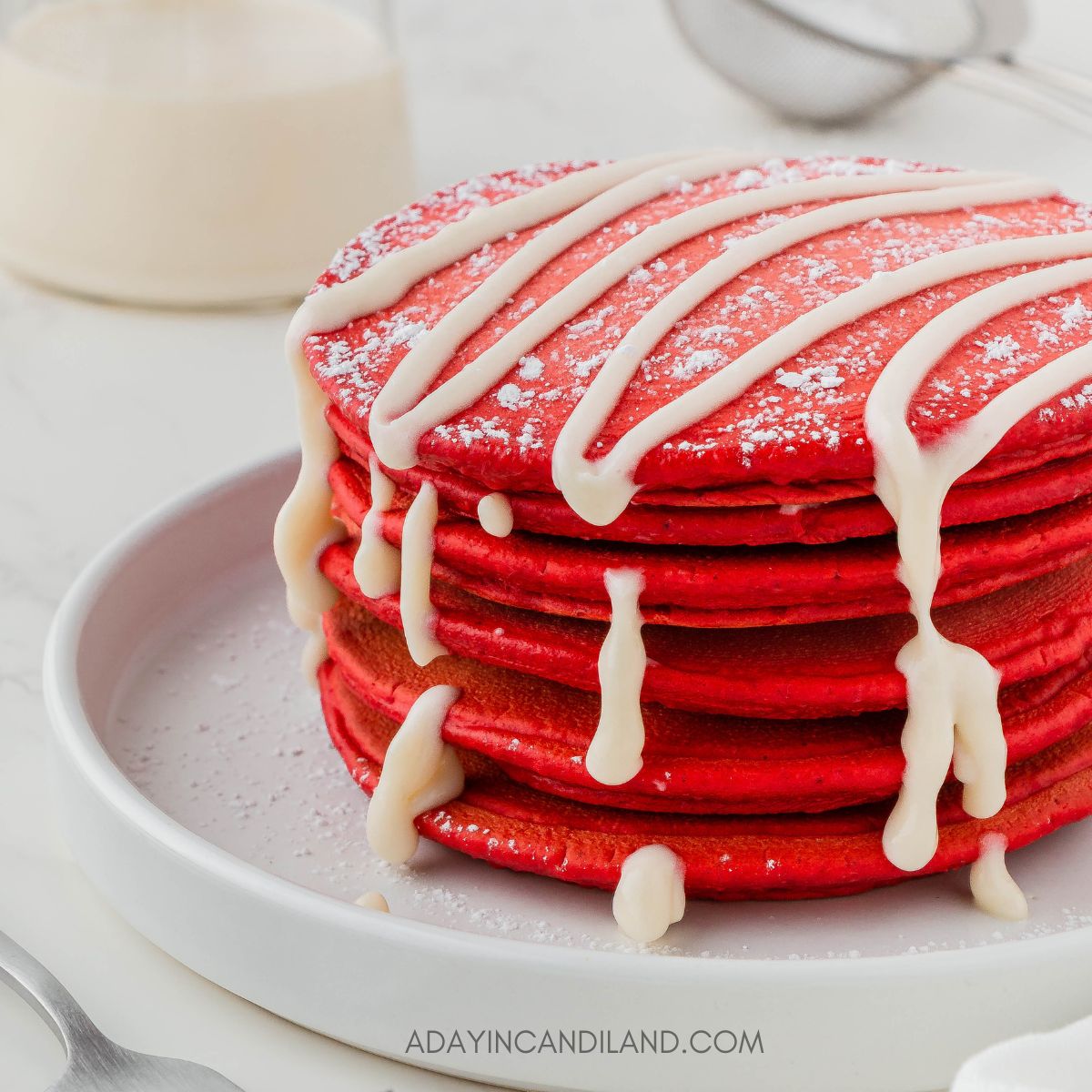 Stack of Red Velvet Pancakes with a cream cheese drizzle on top. 