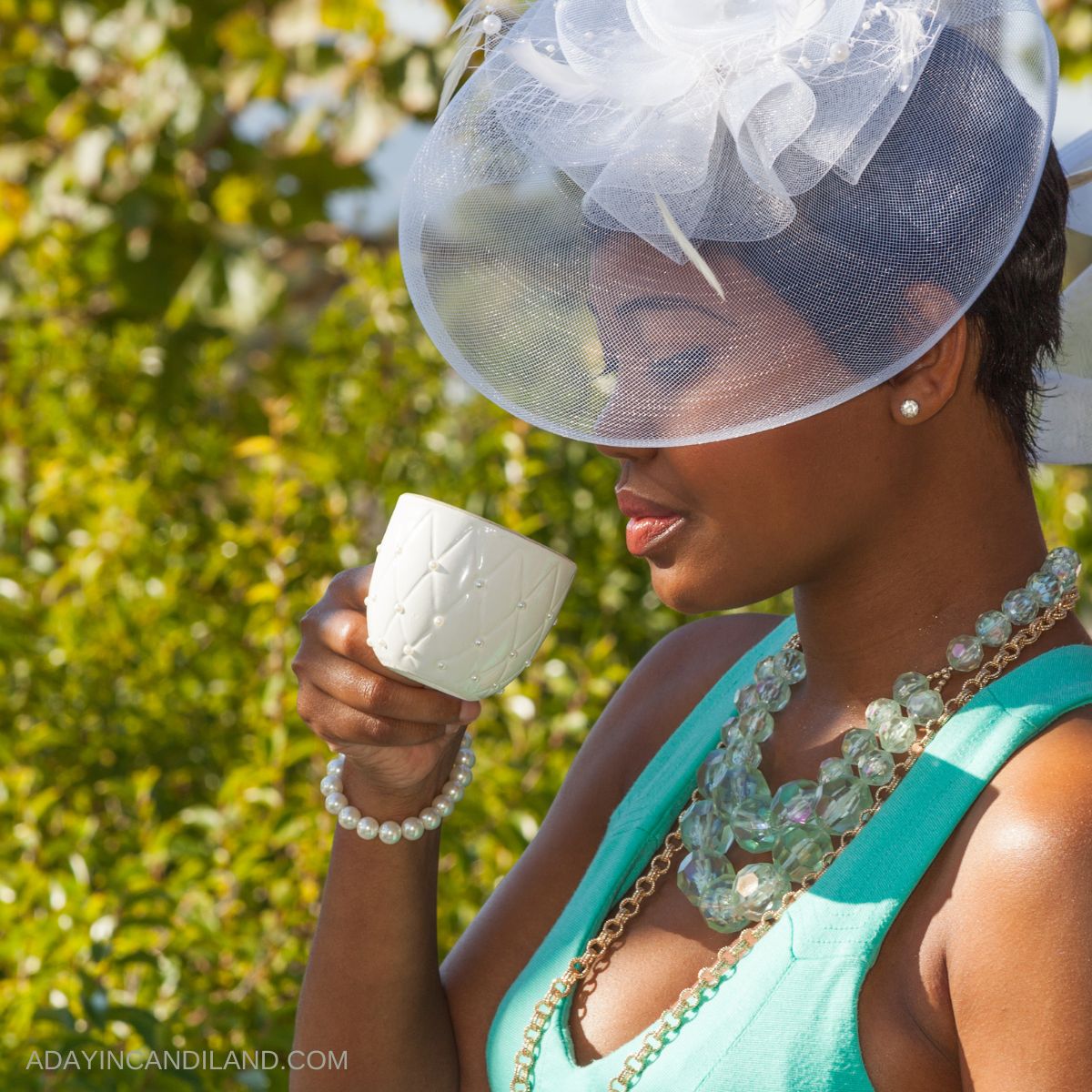 A lovely lady drinking tea wearing a tea party hat. 