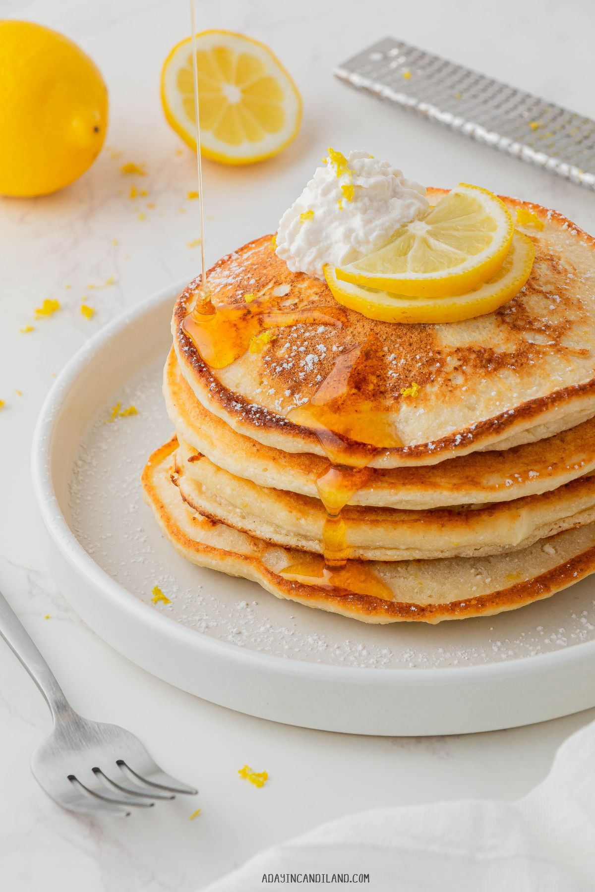 Slack of lemon Ricotta Pancakes with lemon slices on top and a dollop of Ricotta cheese. 