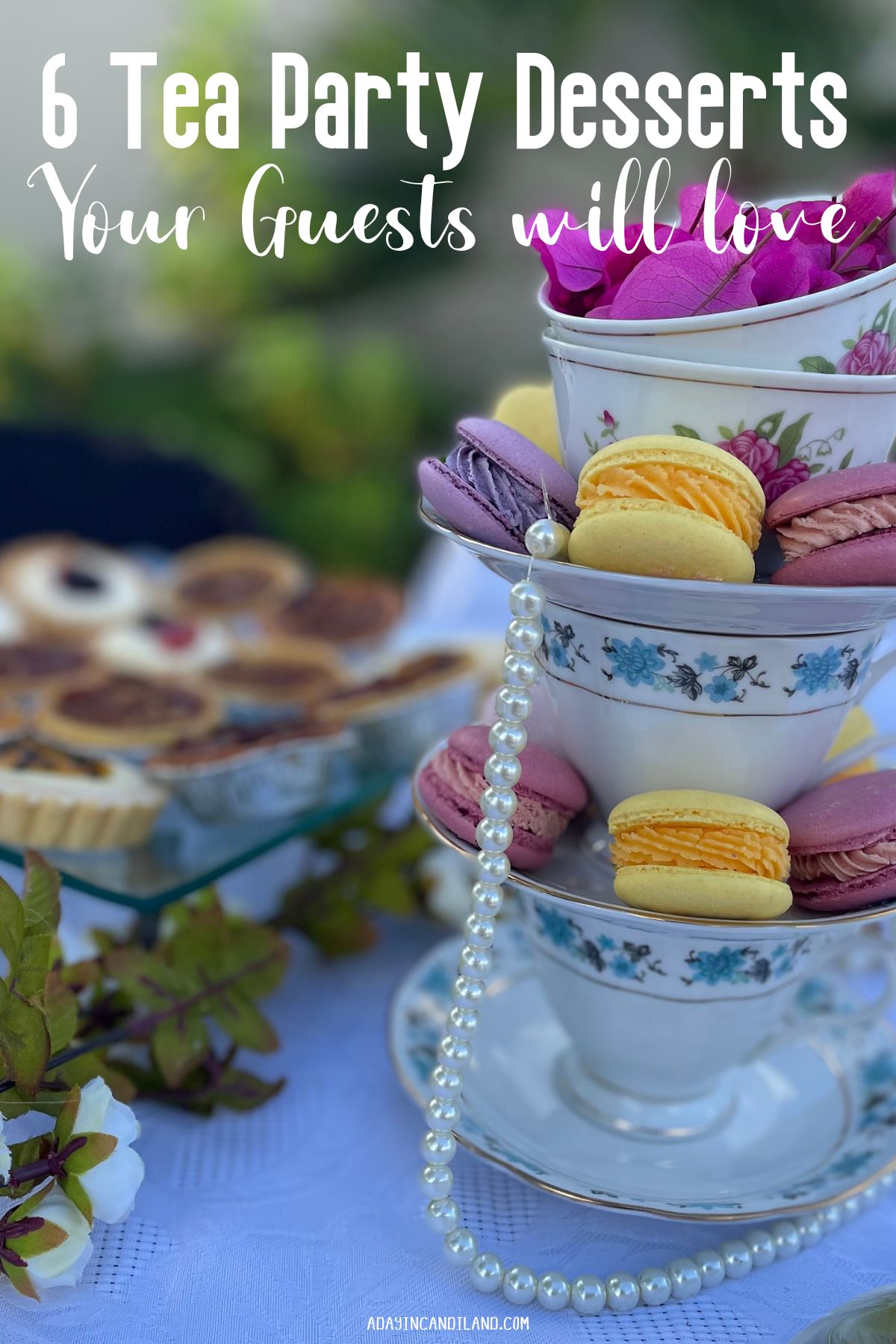 A table of tea party desserts with teacups filled with macarons. 