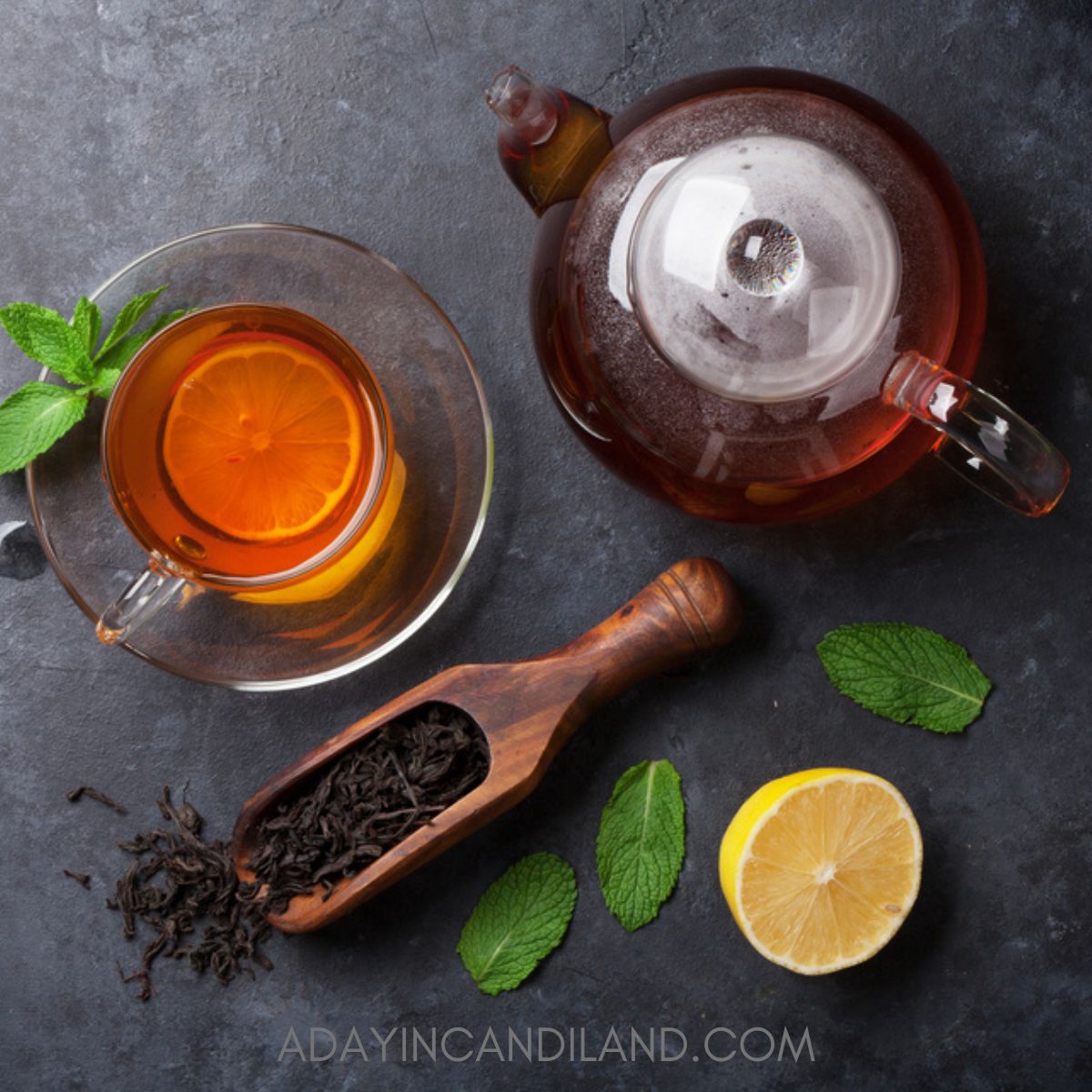 Black board with teacup and teapot on it with some loose tea leaves. 