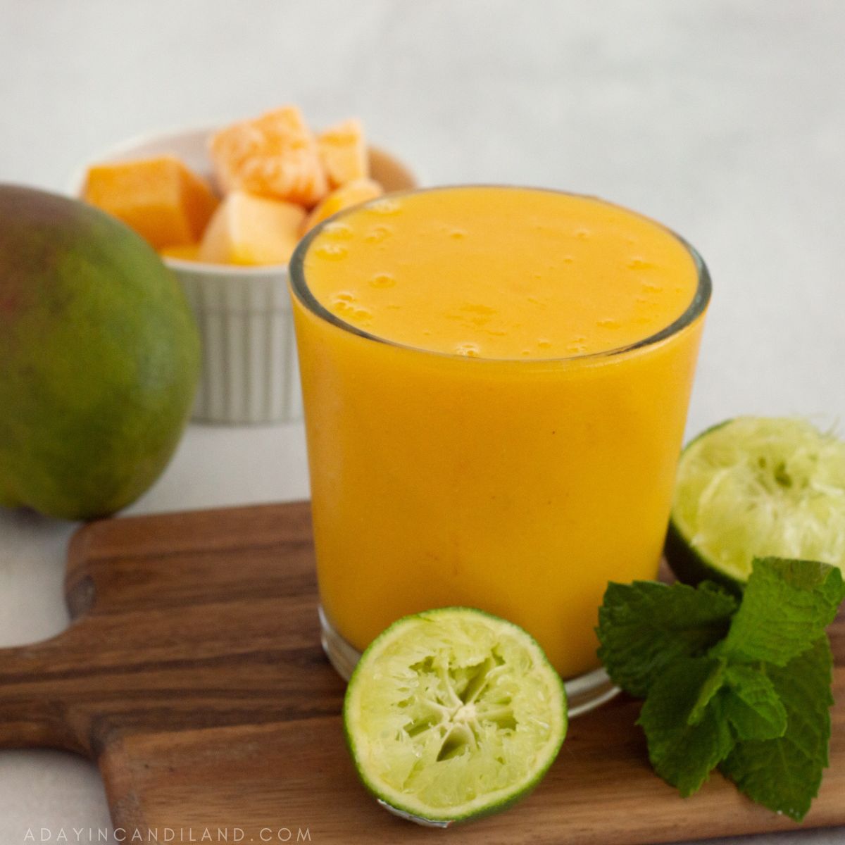 Glass of Mango Detox Smoothie, with a diced mango and mint on the table. 