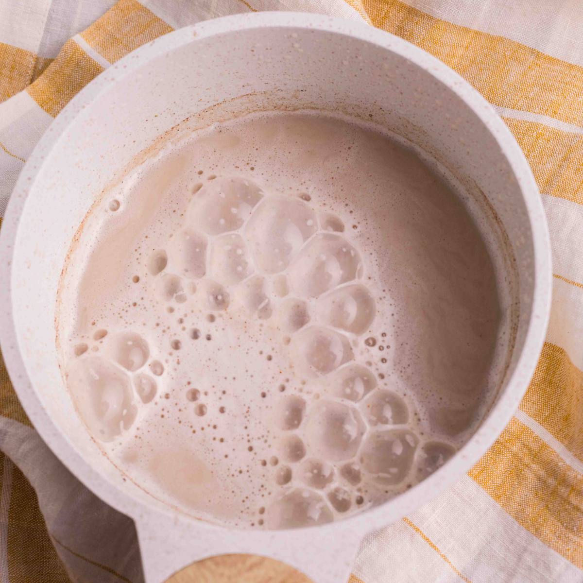Frothy chai latte in the saucepan after blending.