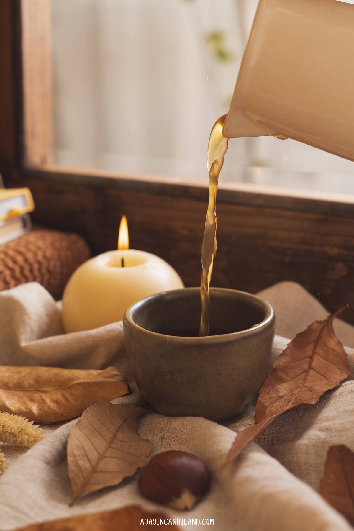 Cup of Earl Grey tea being poured with a candle next to it. 