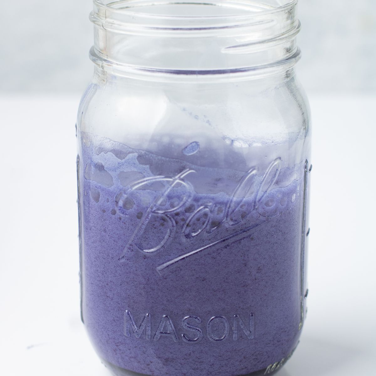 Butterfly pea powder frothed with warm water until foamy and purple blue in a mason jar.
