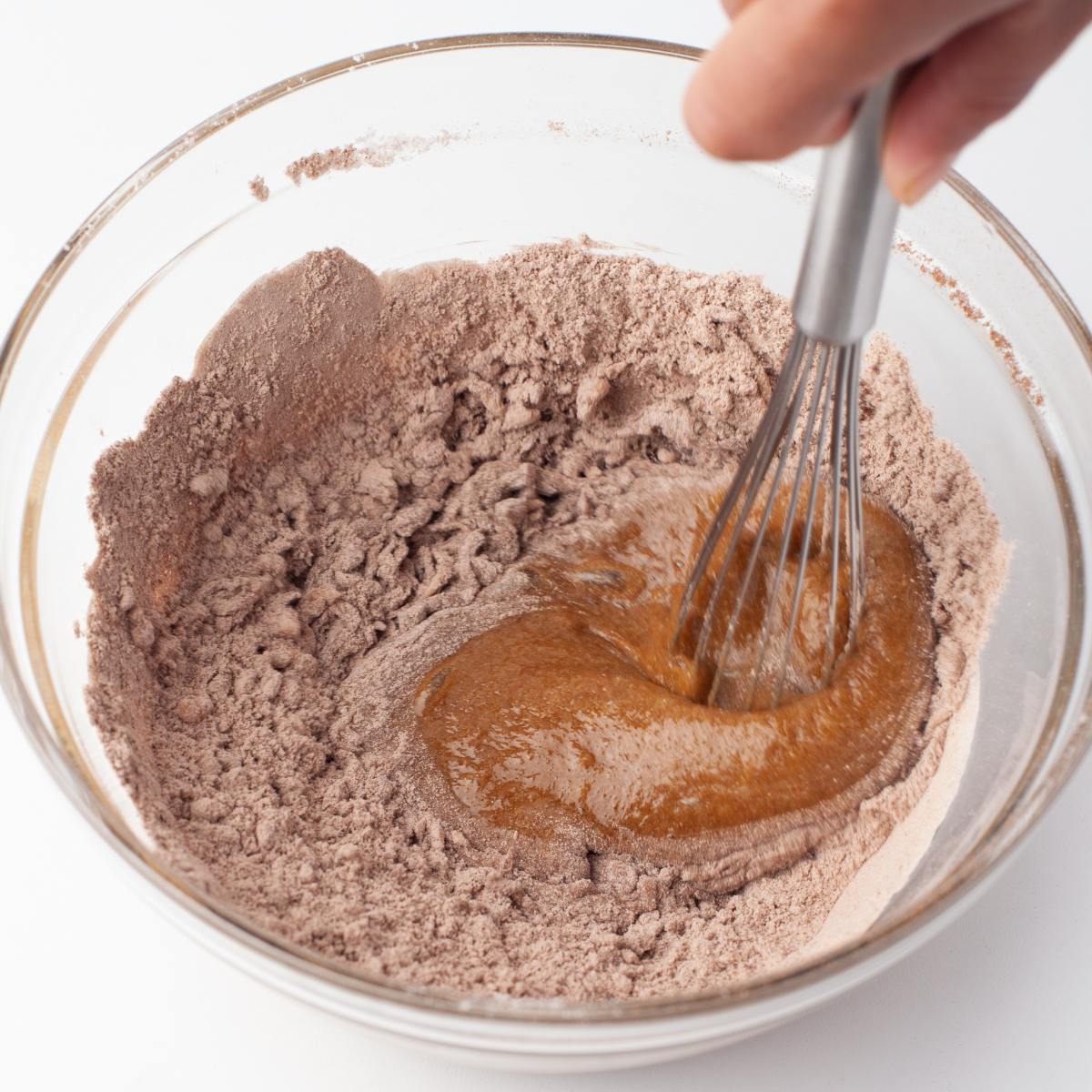 Flour, cocoa powder and salt being whisked into the wet ingredients.