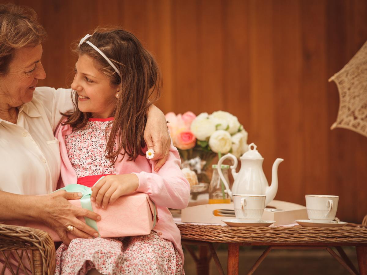 Grandma and girl at a tea table talking and having tea. 