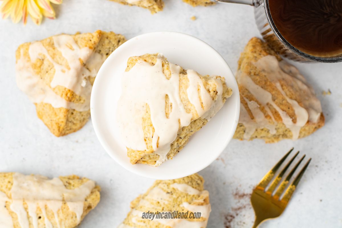 Cup of Tea in the corner, plate of an Earl Grey Scone, with a gold fork in the corner.