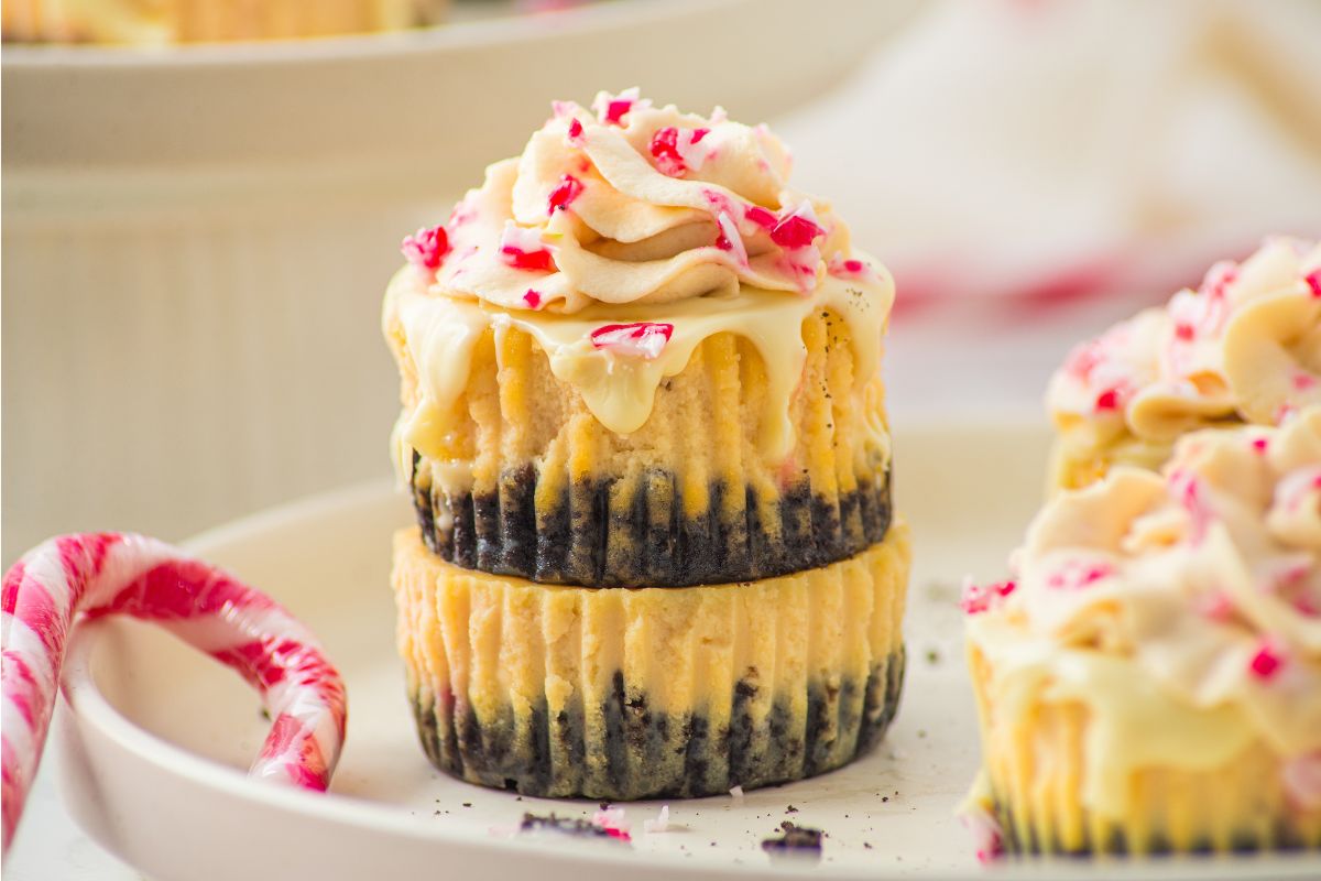 2 stacked mini peppermint cheesecakes on a plate with some candy canes.