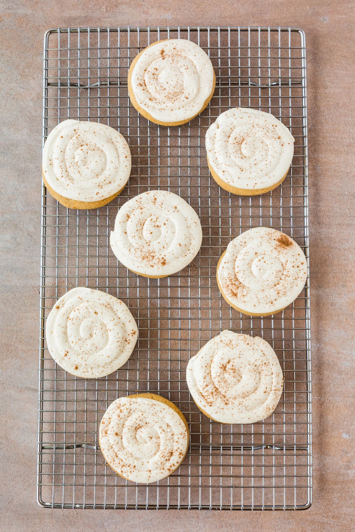 Frosted caramel pumpkin cookies dusted with cinnamon.