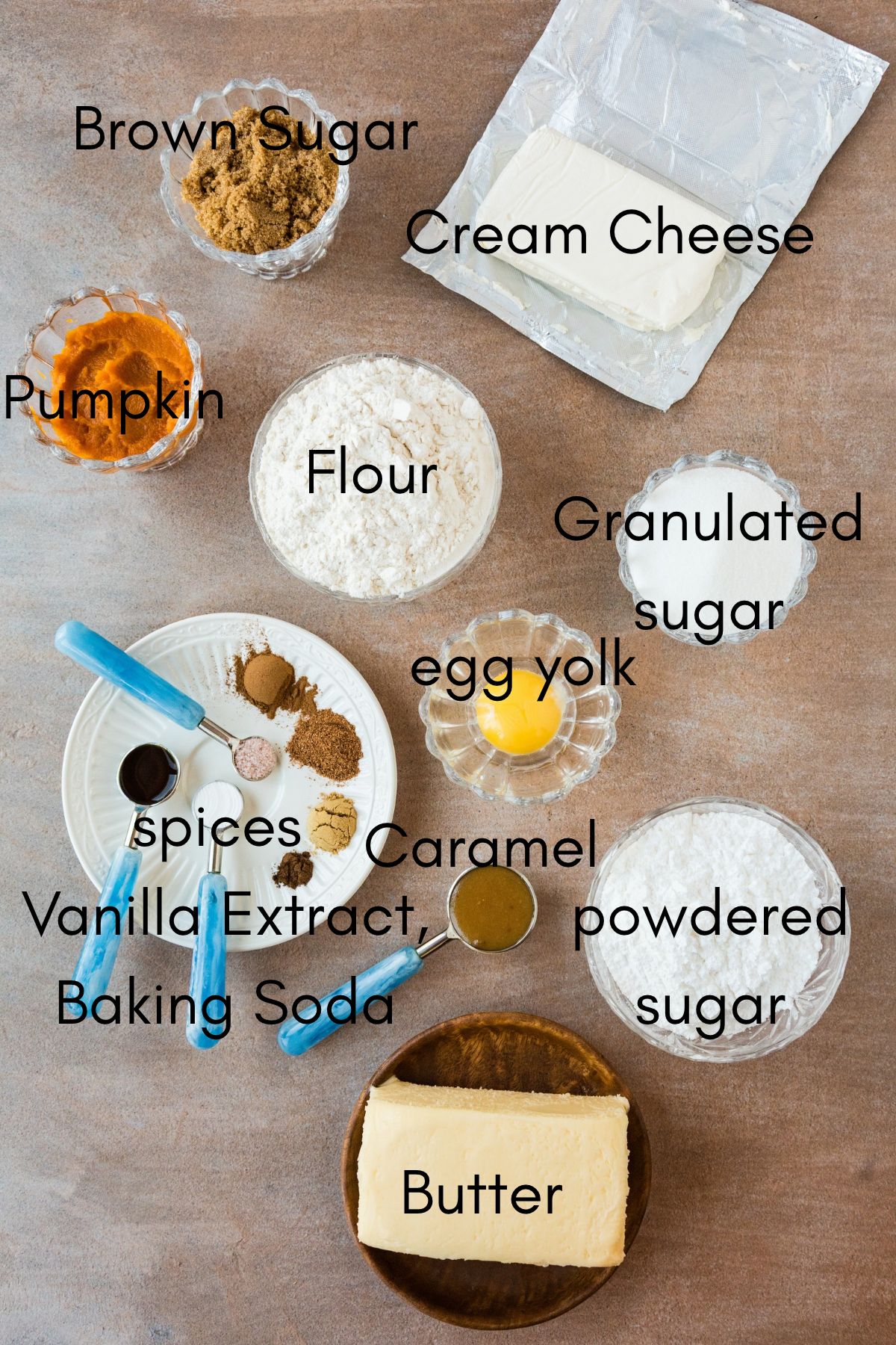 Labeled caramel pumpkin cookie ingredients: brown sugar, cream cheese, pumpkin, flour, granulated sugar, egg yolk, spices, caramel, vanilla extract, baking soda, powdered sugar and butter.