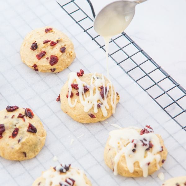 Drizzle the orange glaze over the baked cookies using a spoon.