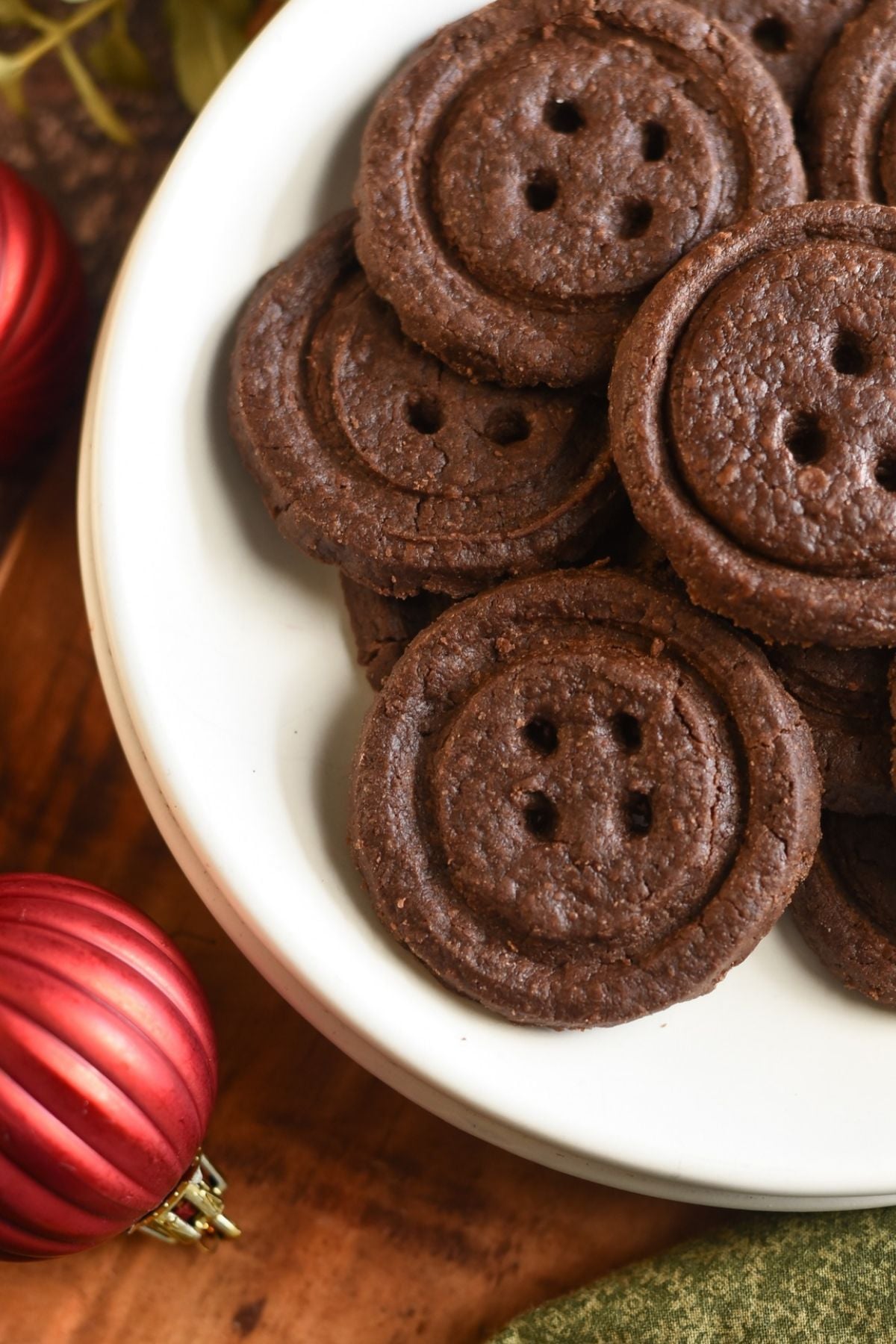 White Plate of Chocolate Shortbread Cookies, next to a  Christmas Ornament. 