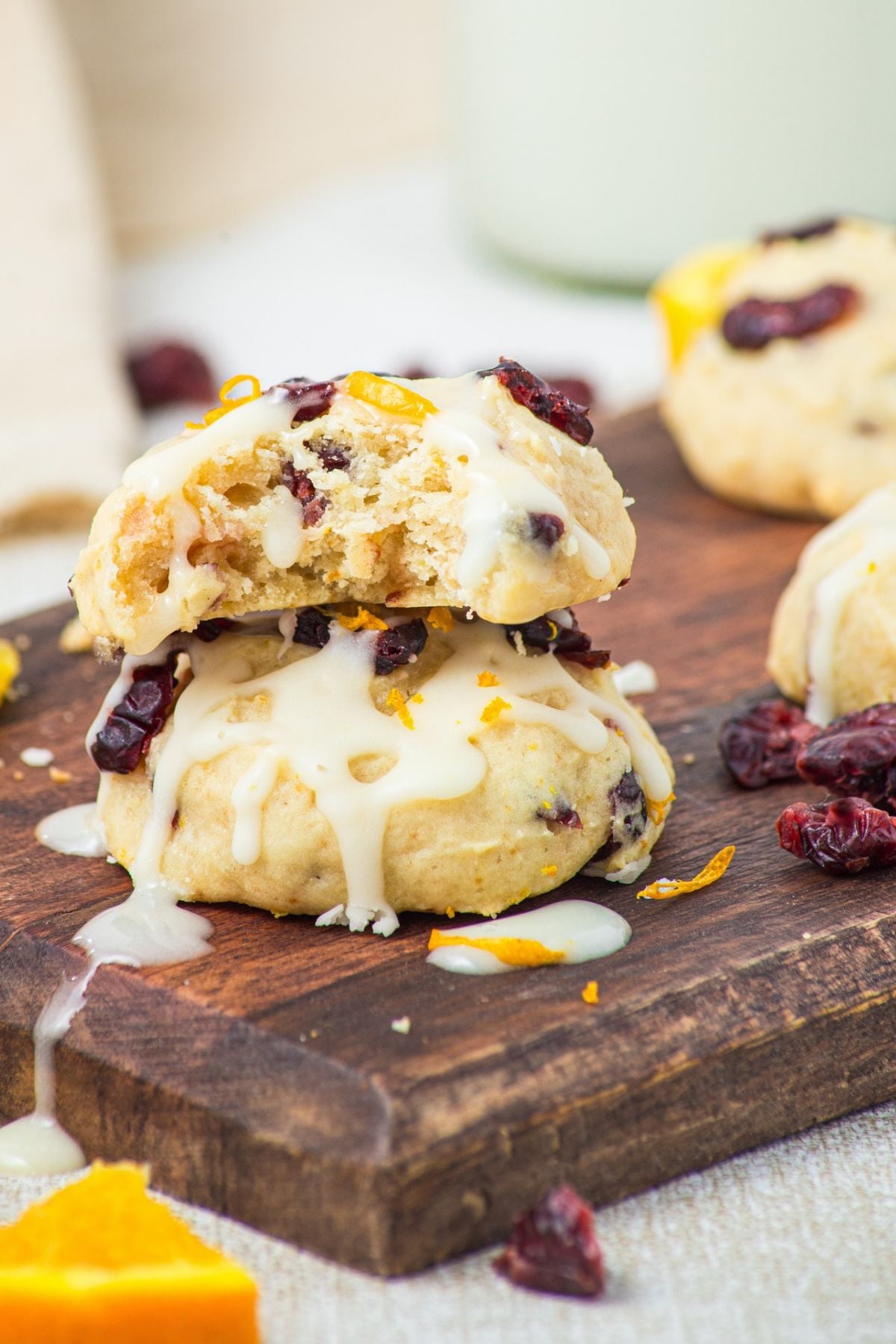 Two cookies stacked with drizzled orange glaze and a bite out of the top cookie.