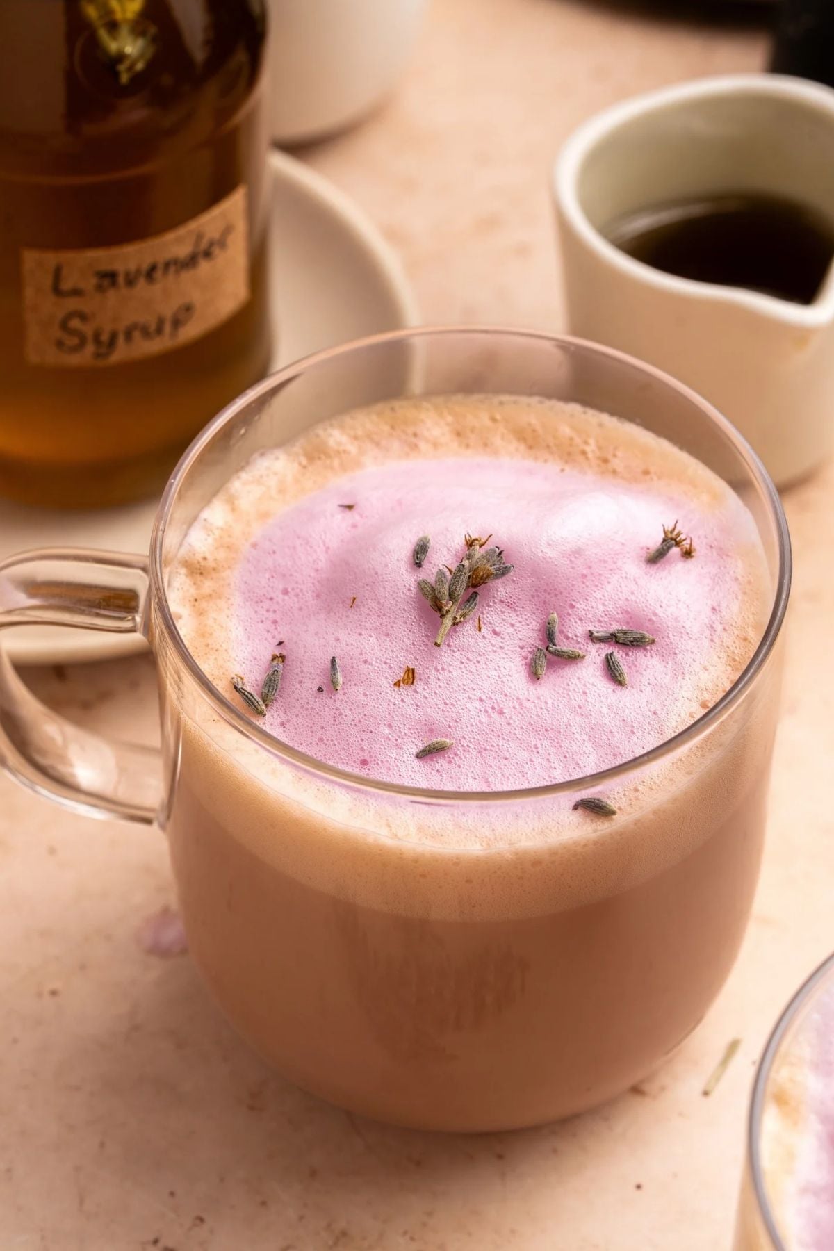 Glass mug of Lavender Latte with lavender buds on top.