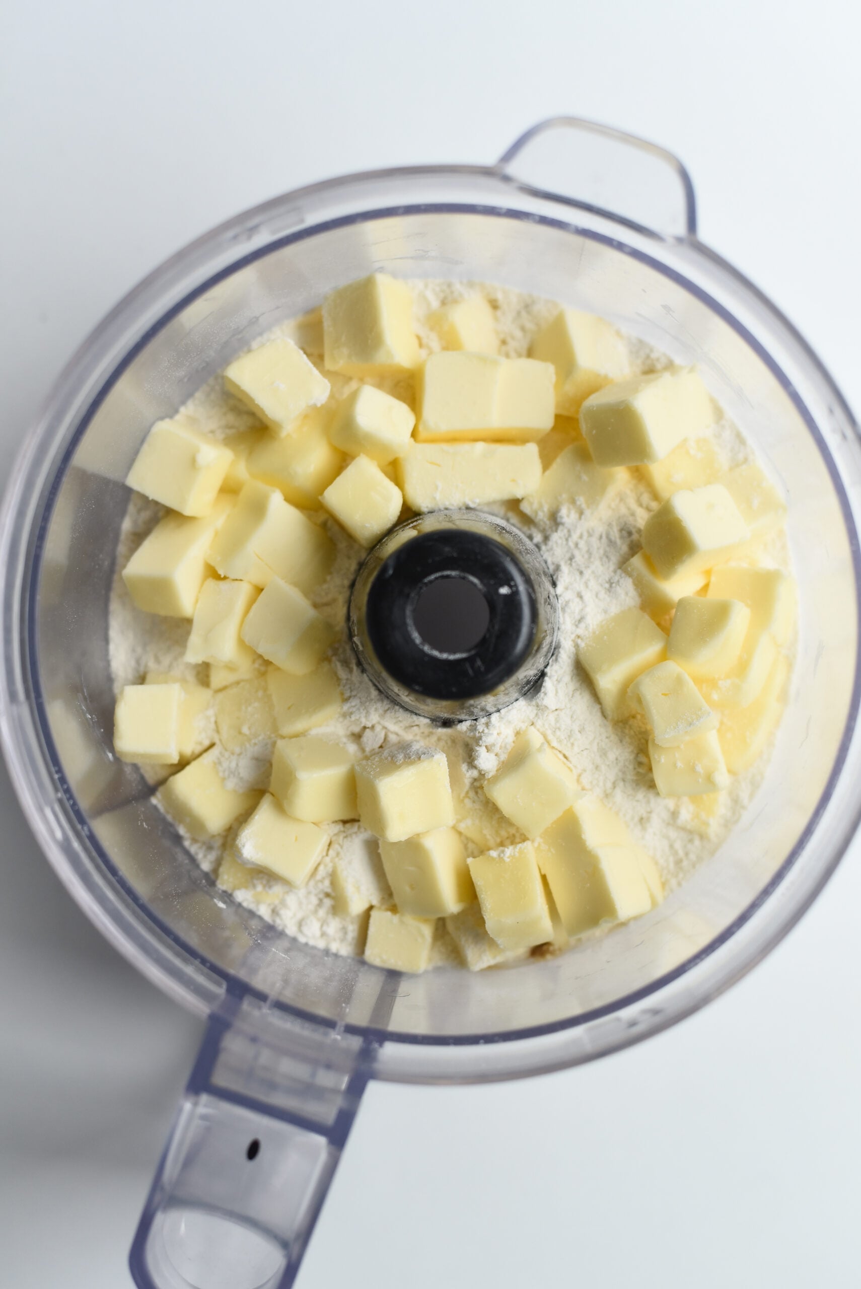 Chopped Butter and Sugar in a food processing bowl.