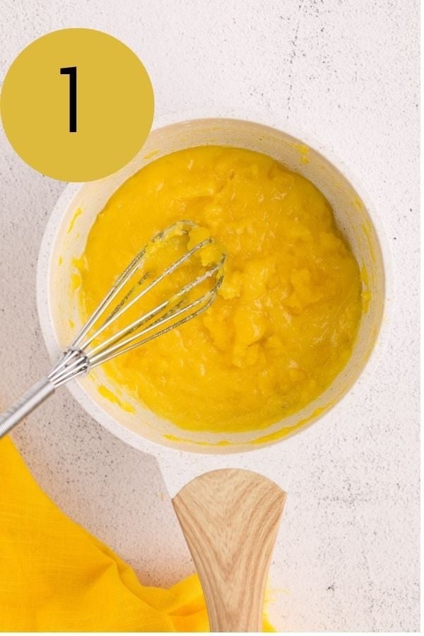 Egg yolks and sugar whisked together in a white saucepan.