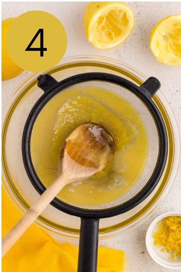 Lemon curd pressed through a fine mesh strainer into a glass bowl.