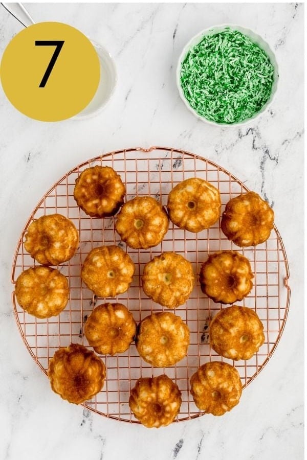 Coconut tinted green in a bowl beside the cooled mini bundt cakes.